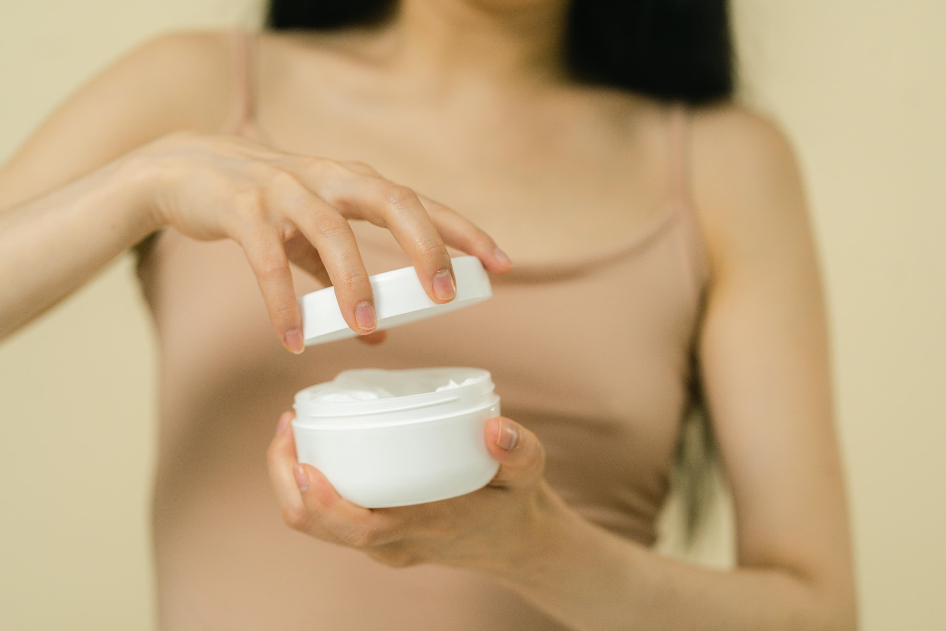 Person opening a jar of moisturizer, skincare routine